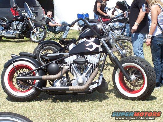 Side view of a black custom motorcycle with white flames and red-rimmed wheels