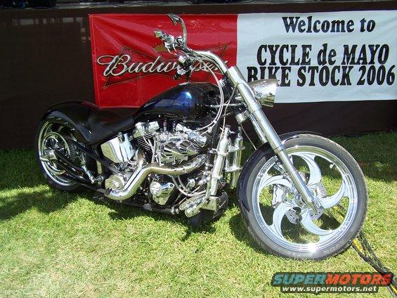 Black motorcycle with chrome accents parked on grass, with a banner reading "Welcome to CYCLE de MAYO BIKE STOCK 2006" behind it
