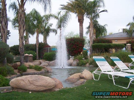 Resort scene with fountain, palm trees, and lounge chairs