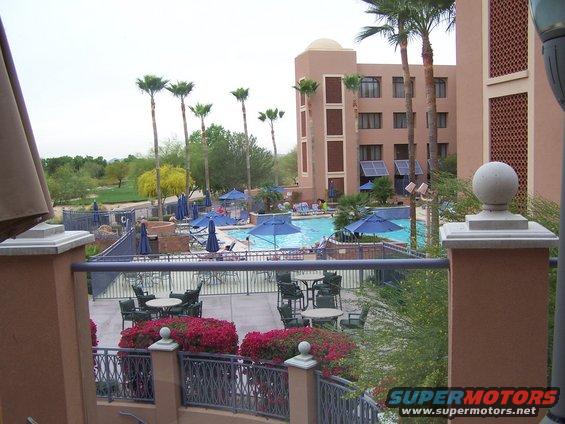 Resort with pool, palm trees, and golf course in background