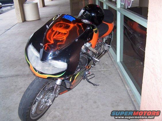 Motorcycle front with flame and snake airbrushing, black helmet on seat