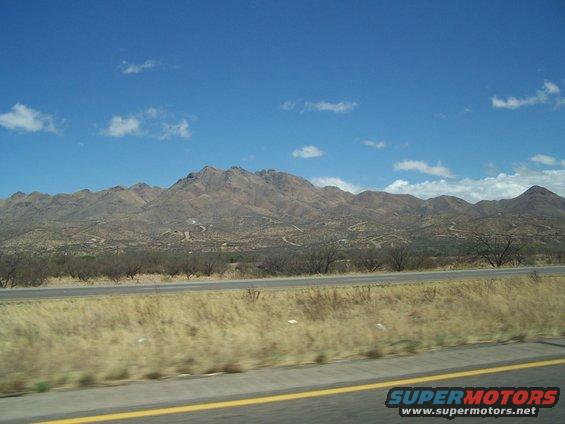 Desert landscape with mountains under a blue sky with clouds, a highway in the foreground