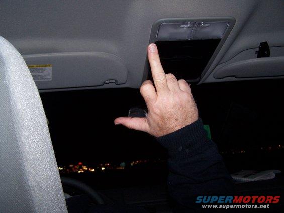 hand giving middle finger inside car at night, with city lights in distance