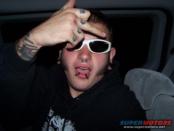 Man with sunglasses and piercings giving the finger
