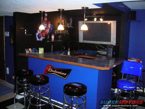Home bar with blue counter, black stools with Ford logos, and a Budweiser sign on the front