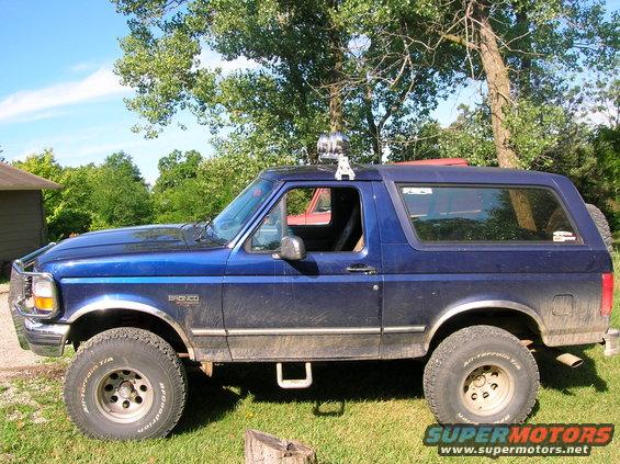 Blue 1994 Ford Bronco side view with off-road tires and roof lights