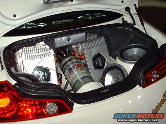 White car trunk with dual subwoofers, amplifiers, and nitrous oxide tank