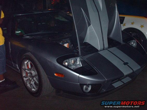Gray Ford GT with hood open, racing stripes. Another car with stars is behind it