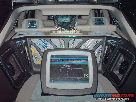 Interior view of a custom car with large screen displaying a Dodge Magnum
