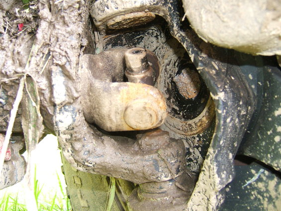 Close-up of a muddy suspension component with a bolt and nut