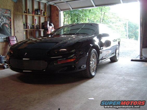 Black Chevrolet Camaro parked in a garage. It has a custom grille