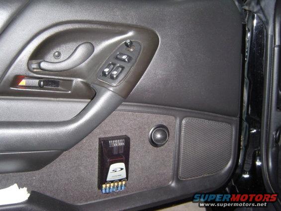 Car door panel with power window controls, speaker, and aftermarket Alpine amplifier