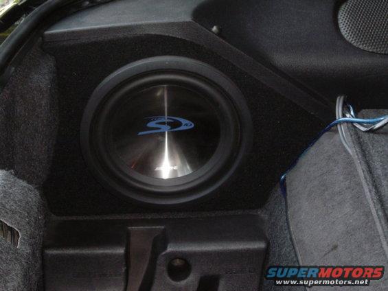 Alpine subwoofer mounted in a black custom enclosure in a car's trunk