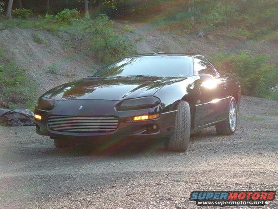 Black 2002 Chevrolet Camaro parked on a gravel road with trees in the background