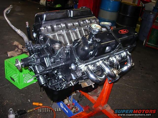Ford V8 engine on an orange stand, with a green crate and tools nearby