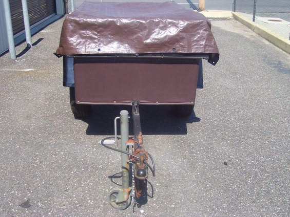 Trailer with brown tarp cover, showing hitch and wheel