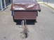1991 Ford Bronco - Rear view of a trailer covered with a brown tarp, parked on asphalt.