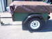 1991 Ford Bronco - A utility trailer is parked outdoors, covered with a brown tarp.