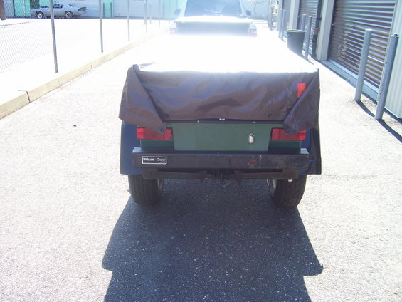 Trailer hitch with a dark brown tarp covering the top, green body, and black bumper