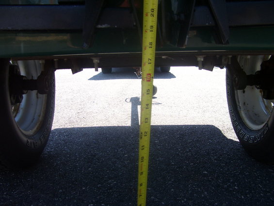 Measuring tape on underside of green vehicle, showing clearance