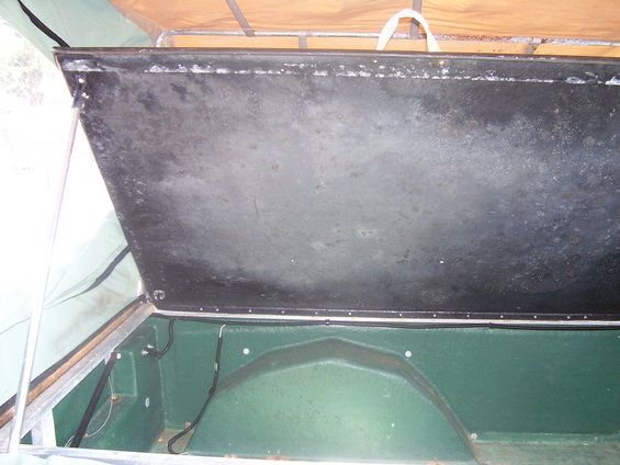 open storage area inside a vehicle, showing green interior and black lid