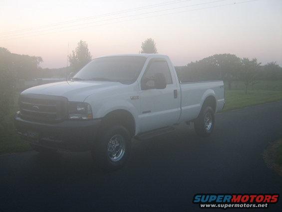 White 2003 Ford F-250 pickup truck parked on asphalt road in foggy conditions