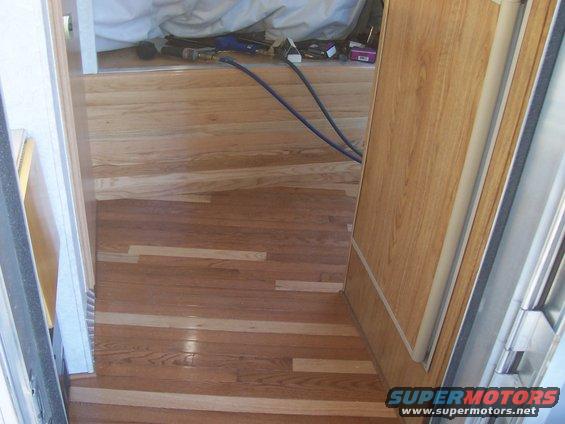 Interior view of a camper with wood paneling and flooring