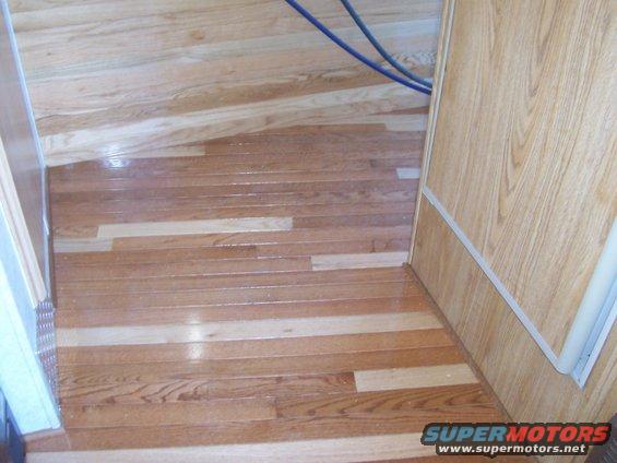 Wooden floor inside a camper with some blue cables visible