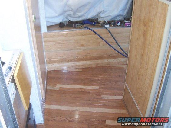 Interior view of a vehicle with hardwood floors, showing tools and hoses on a raised platform