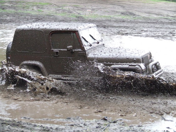 Brown Jeep Wrangler splashing through mud