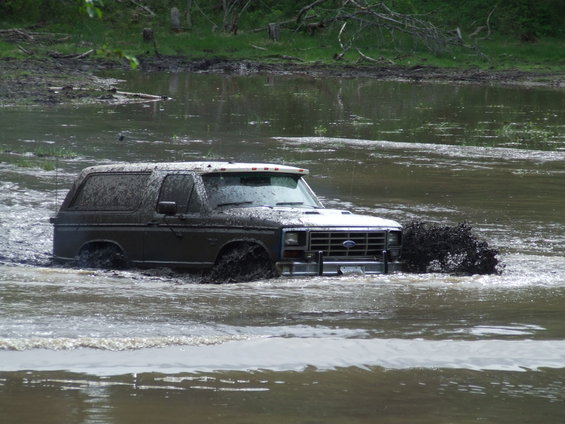 Ford Bronco driving through mud, splashing water and dirt