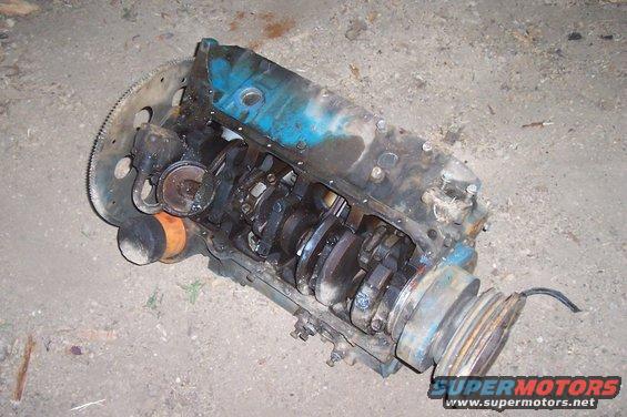 Engine block with crankshaft, oil filter, and pulley system visible. The engine is blue and appears to be disassembled