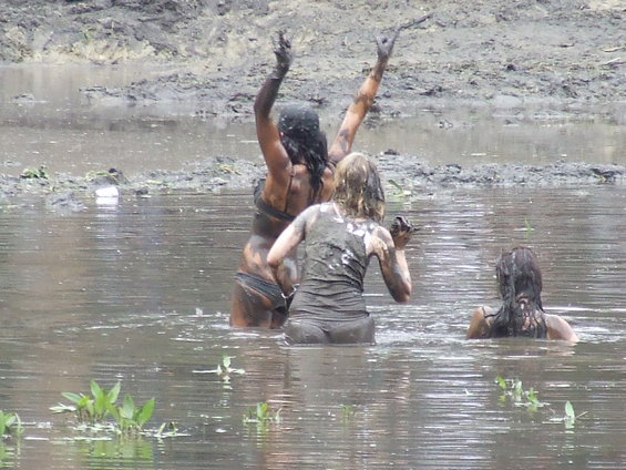 People covered in mud playing in a muddy pool