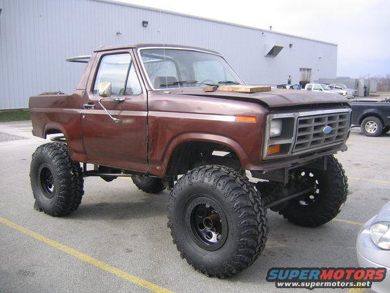 Brown lifted Ford Bronco with large tires parked outside a building