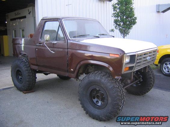 Brown and white Ford Bronco with large tires, lifted suspension, and aftermarket wheels