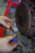 1995 Ford Taurus - A hand applies threadlocker to a bolt near a vehicle's clutch assembly, likely during an engine refresh or swap.