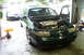 1995 Ford Taurus - The front of a green Ford Taurus is shown with the hood open, revealing the engine bay. Another Taurus is parked behind it.