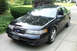 1995 Ford Taurus - A black 1995 Ford Taurus is parked outside a suburban home.