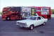 1966 Ford Fairlane - A white 1966 Ford Fairlane is parked in front of a bus decorated with flames and "Hot Rod Power Tour" branding.