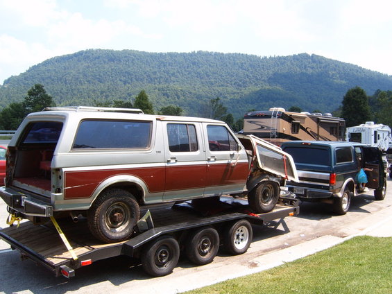 Two-tone SUV on trailer, another SUV and RVs behind it