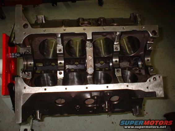Engine block with crankshaft installed, showing cylinder bores and bearing caps