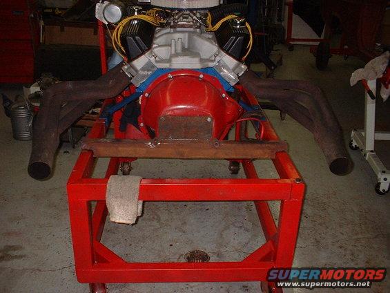 V8 engine with dual exhaust manifolds on a red rolling stand