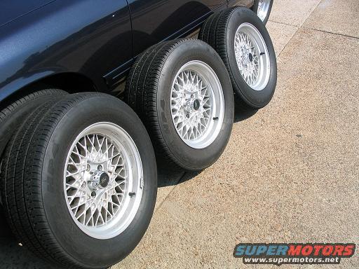 Four aftermarket mesh rims with tires on dark blue car body