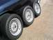 1999 Ford Crown Victoria - Aftermarket mesh rims and tires are displayed next to a dark blue vehicle.