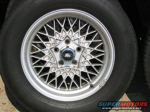 Close-up of a silver wire-style Ford wheel with a black center cap