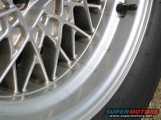 Close-up of a silver alloy wheel and tire, showing some cracks on the rim