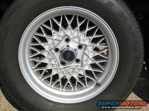Silver wire-spoke wheel with a black Ford center cap and tire