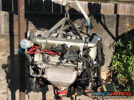 Engine assembly suspended by straps, showing intake manifold and wiring