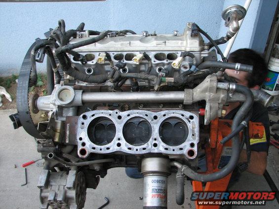 Engine block with three cylinders exposed, mounted on an orange engine stand