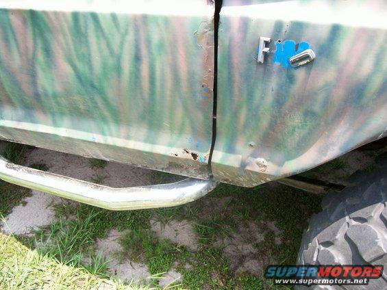 Side view of a camo-painted Ford F-150 truck with a chrome step bar and large tire